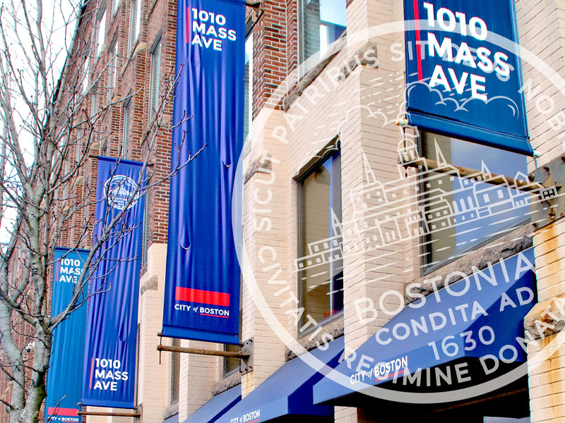 Blue vertical banners along a brick building reading 1010 Mass Ave in Boston.